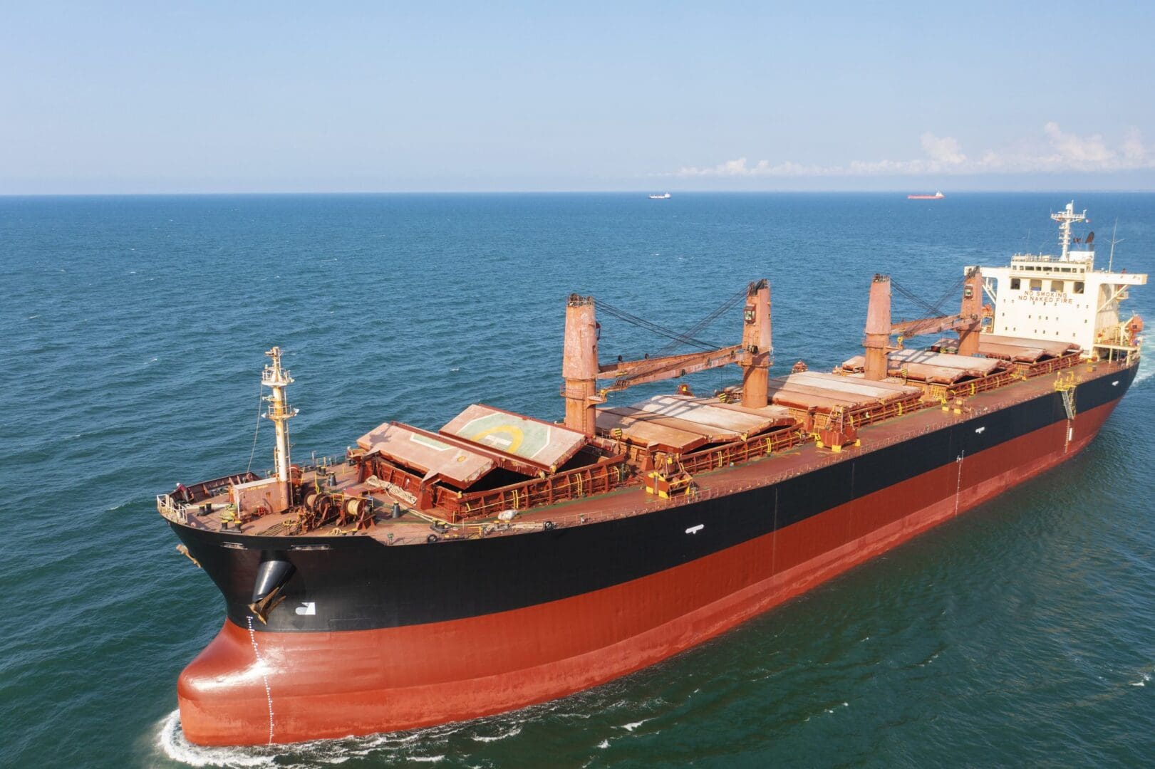 Large cargo ship sailing on the ocean under clear sky.