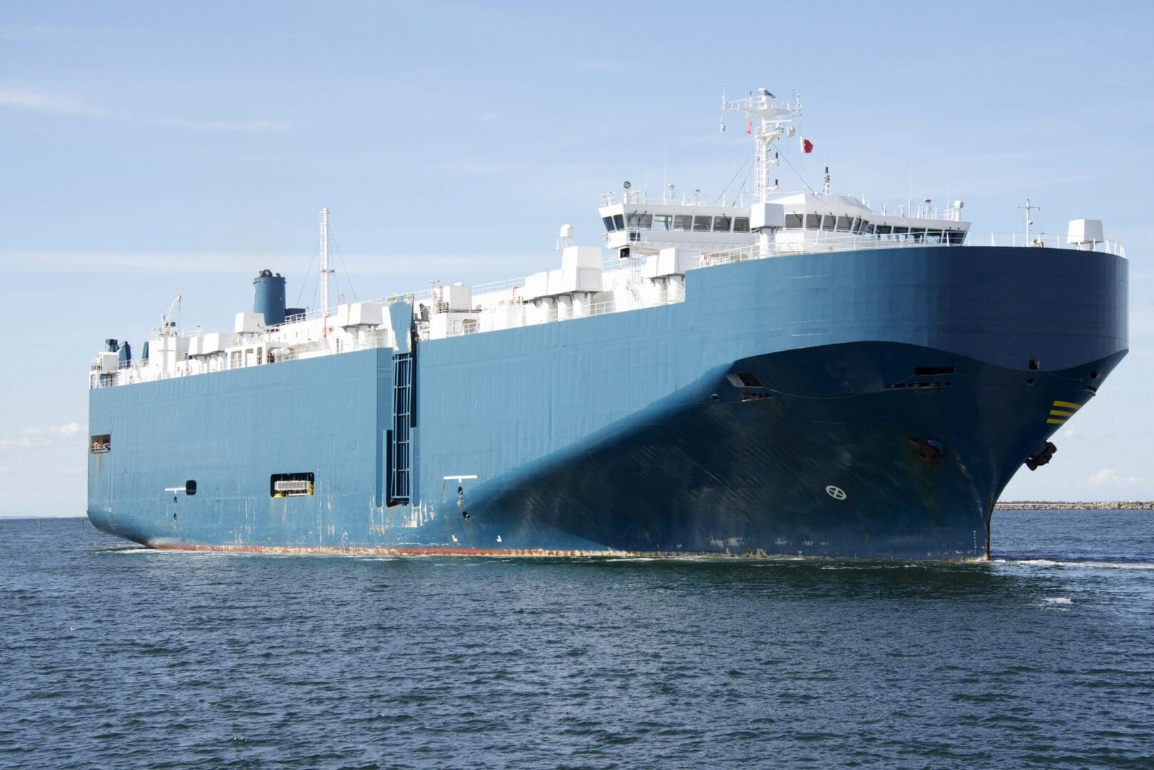 Large cargo ship sailing on calm water under clear sky.